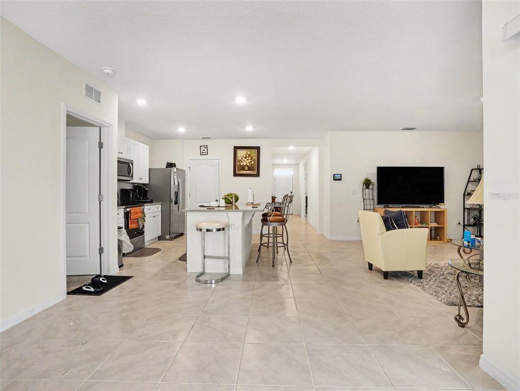 An open-concept kitchen and living area features tile flooring, a central island, and white cabinetry — 3362 ARUBA WAY, HAINES CITY, FL
