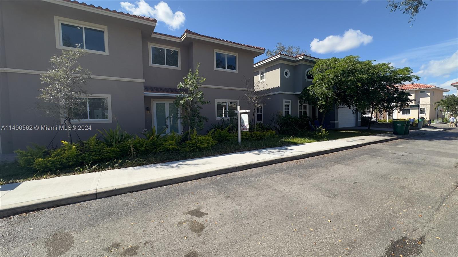 A two-story gray townhouse with a tiled roof and a front yard sits beside a street — 3562 Forest View Cir, Dania Beach FL 33312, DANIA BEACH, FL