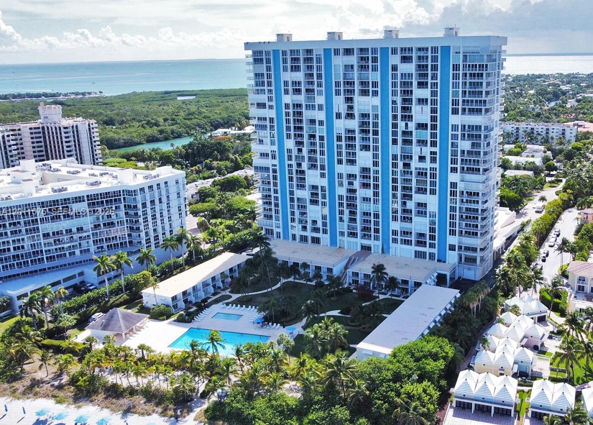 An aerial view shows a tall blue and white residential building with a swimming pool below — 881 Ocean Dr # 7D, Key Biscayne FL 33149, KEY BISCAYNE, FL