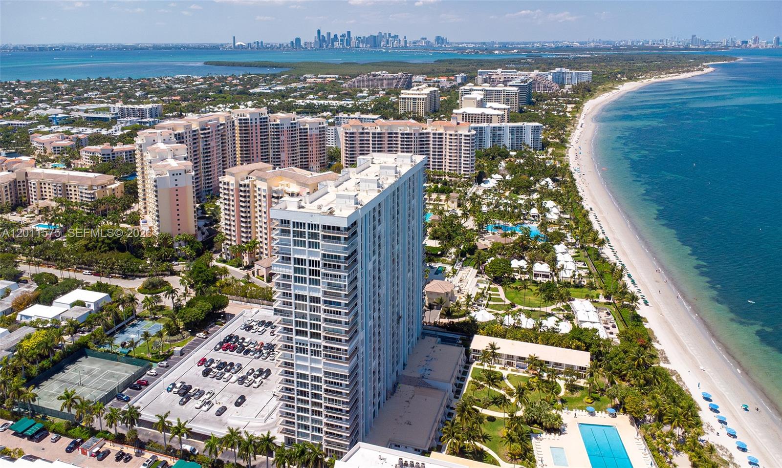 An aerial view shows a tall residential building surrounded by a beach, pools, and parking — 881 Ocean Dr # 7D, Key Biscayne FL 33149, KEY BISCAYNE, FL