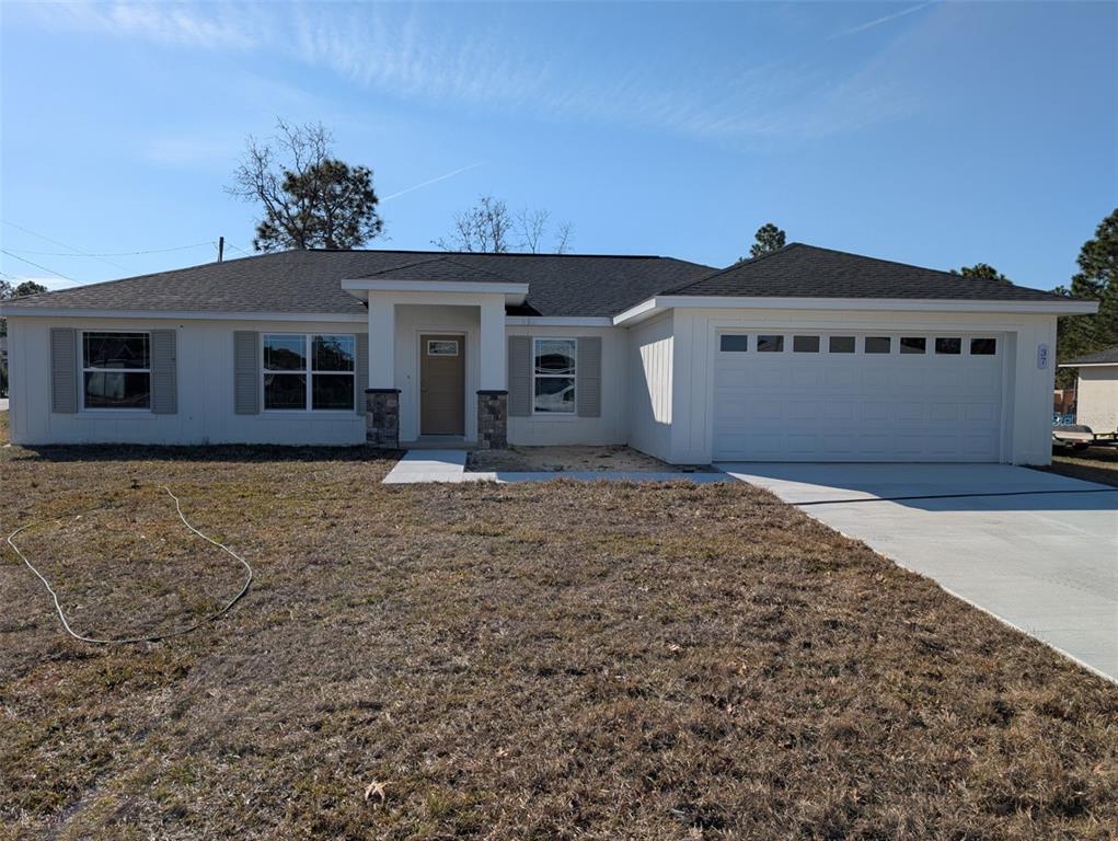 A single-story house with white siding, a two-car garage, and a stone-accented front entryway — 37 FIR DRIVE TRACE, OCALA, FL
