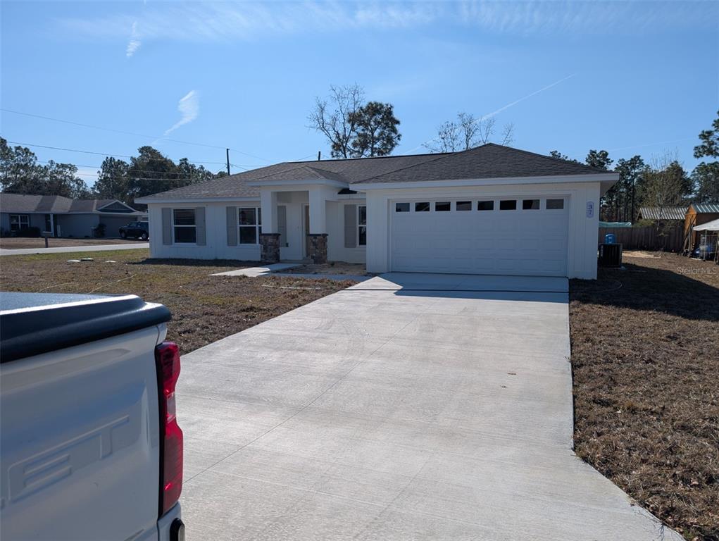 A single-story house with a white exterior, stone accents, and a concrete driveway — 37 FIR DRIVE TRACE, OCALA, FL