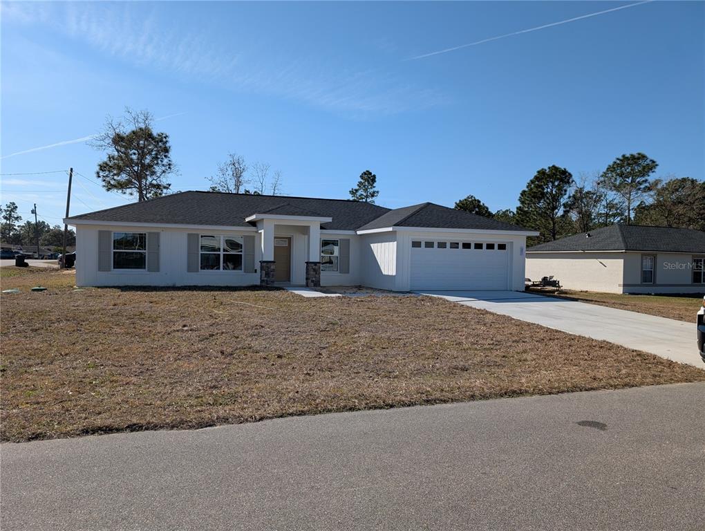 A single-story white house with a dark shingled roof and a two-car garage — 37 FIR DRIVE TRACE, OCALA, FL