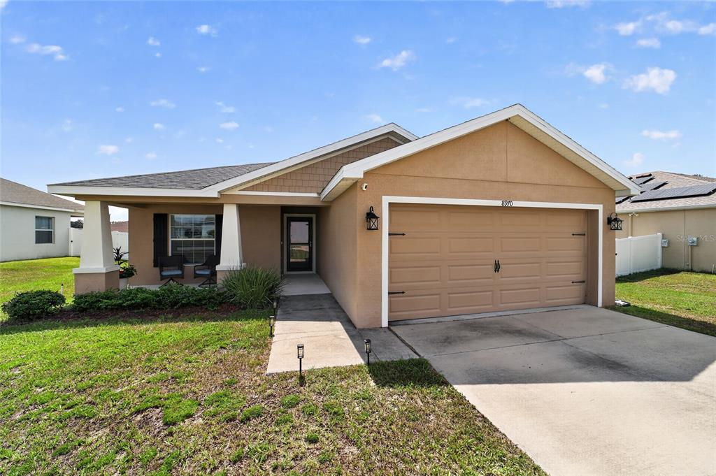 A tan single-story house with a two-car garage and a covered front porch — 8970 SE 49TH COURT ROAD, OCALA, FL