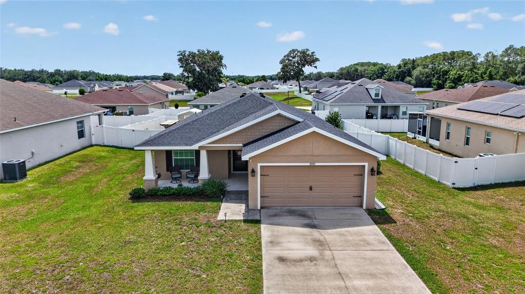 An aerial view of a single-story suburban house with a tan exterior and two-car garage — 8970 SE 49TH COURT ROAD, OCALA, FL