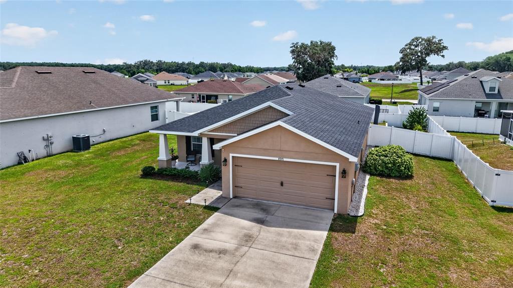 An aerial view of a tan single-story house with a two-car garage and white fencing — 8970 SE 49TH COURT ROAD, OCALA, FL