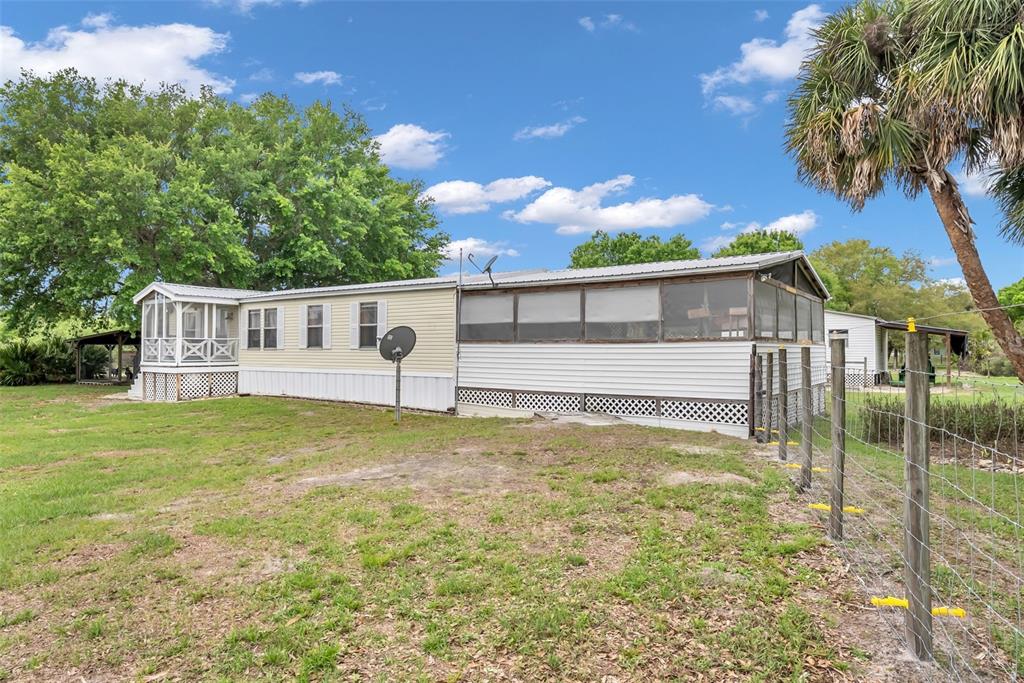 A mobile home with a screened-in porch and a metal roof sits on a grassy lot — 17255 NW 272ND STREET, OKEECHOBEE, FL