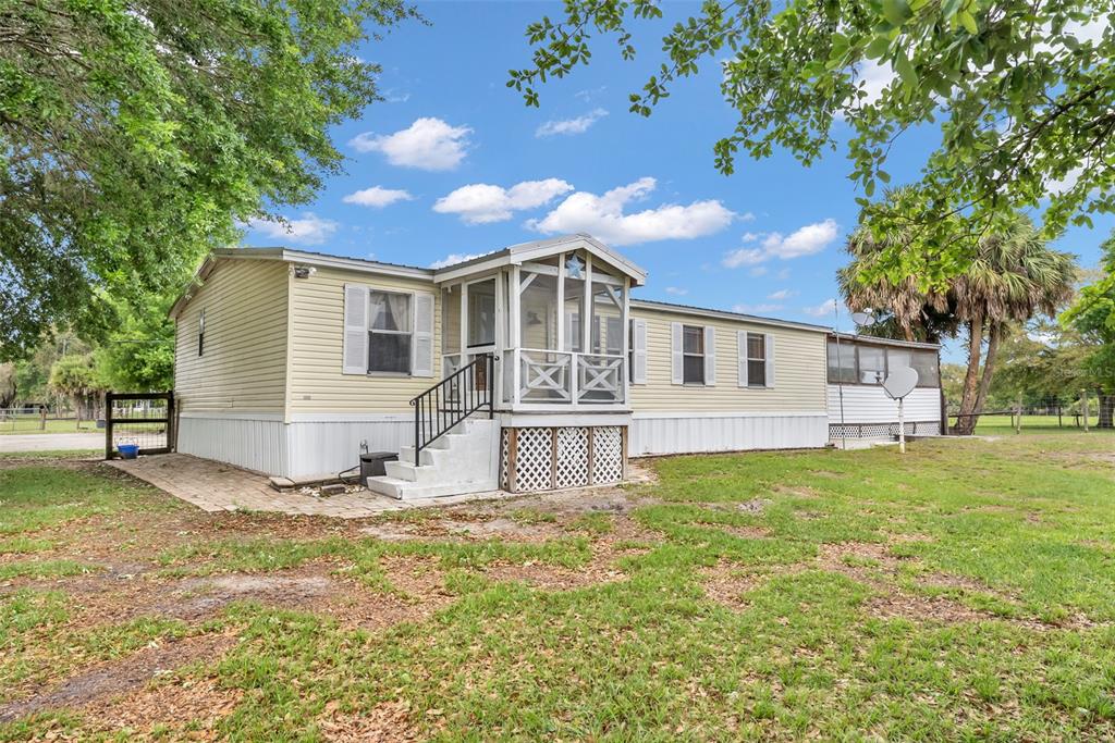 A light yellow manufactured home with a screened-in front porch and white lattice skirting — 17255 NW 272ND STREET, OKEECHOBEE, FL