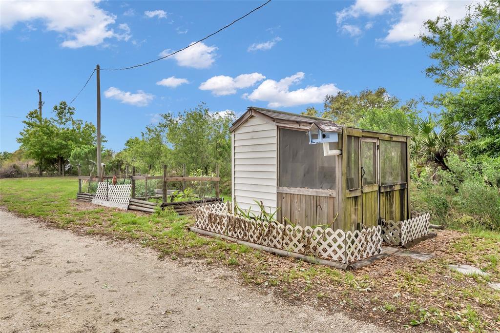 A small wooden shed with a screened enclosure sits next to a garden on a lot — 17255 NW 272ND STREET, OKEECHOBEE, FL