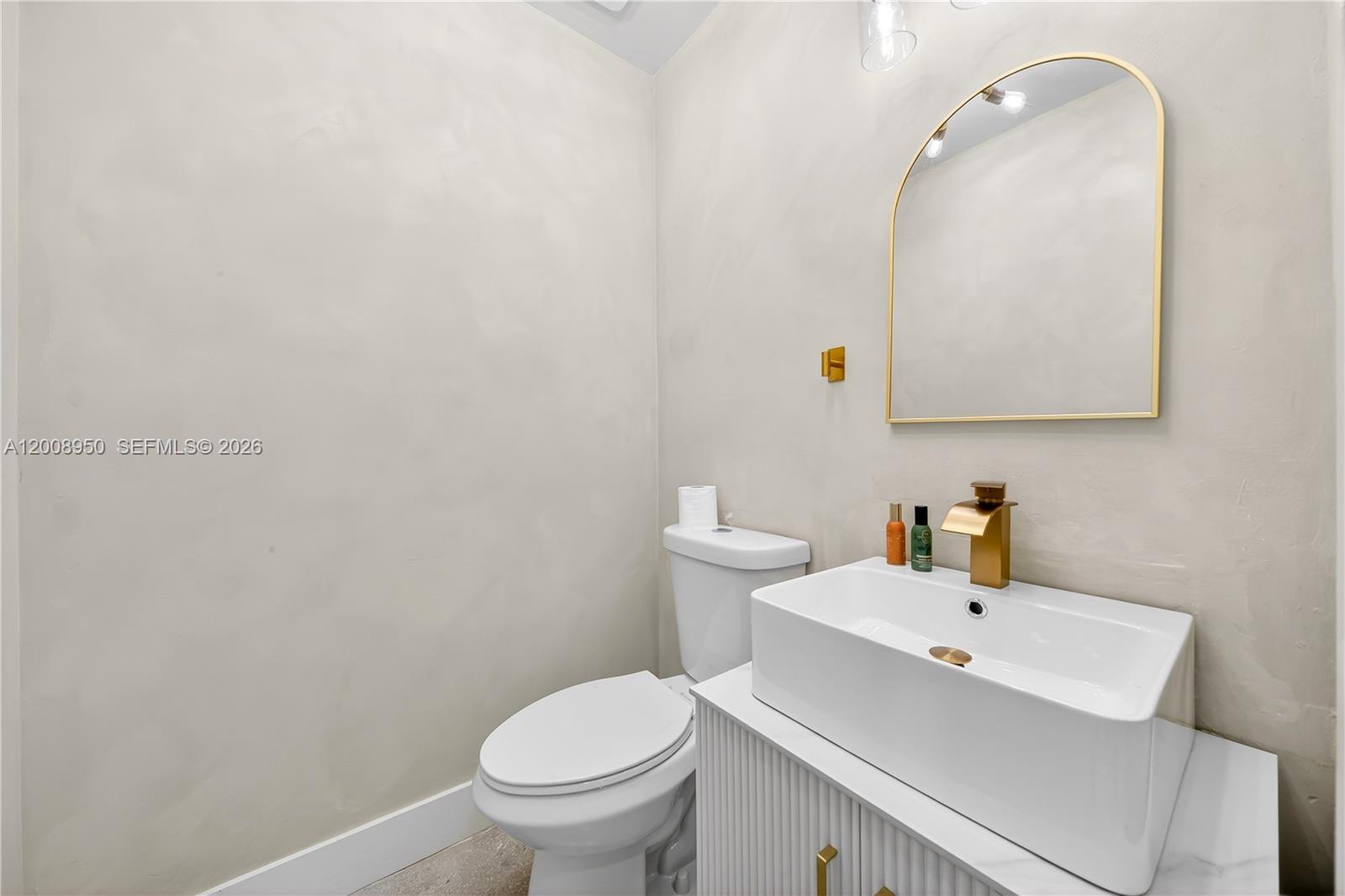A small bathroom features a white vessel sink, gold faucet, and an arched wall mirror — 12305 SW 133rd Ct # 26, Miami FL 33186, MIAMI, FL