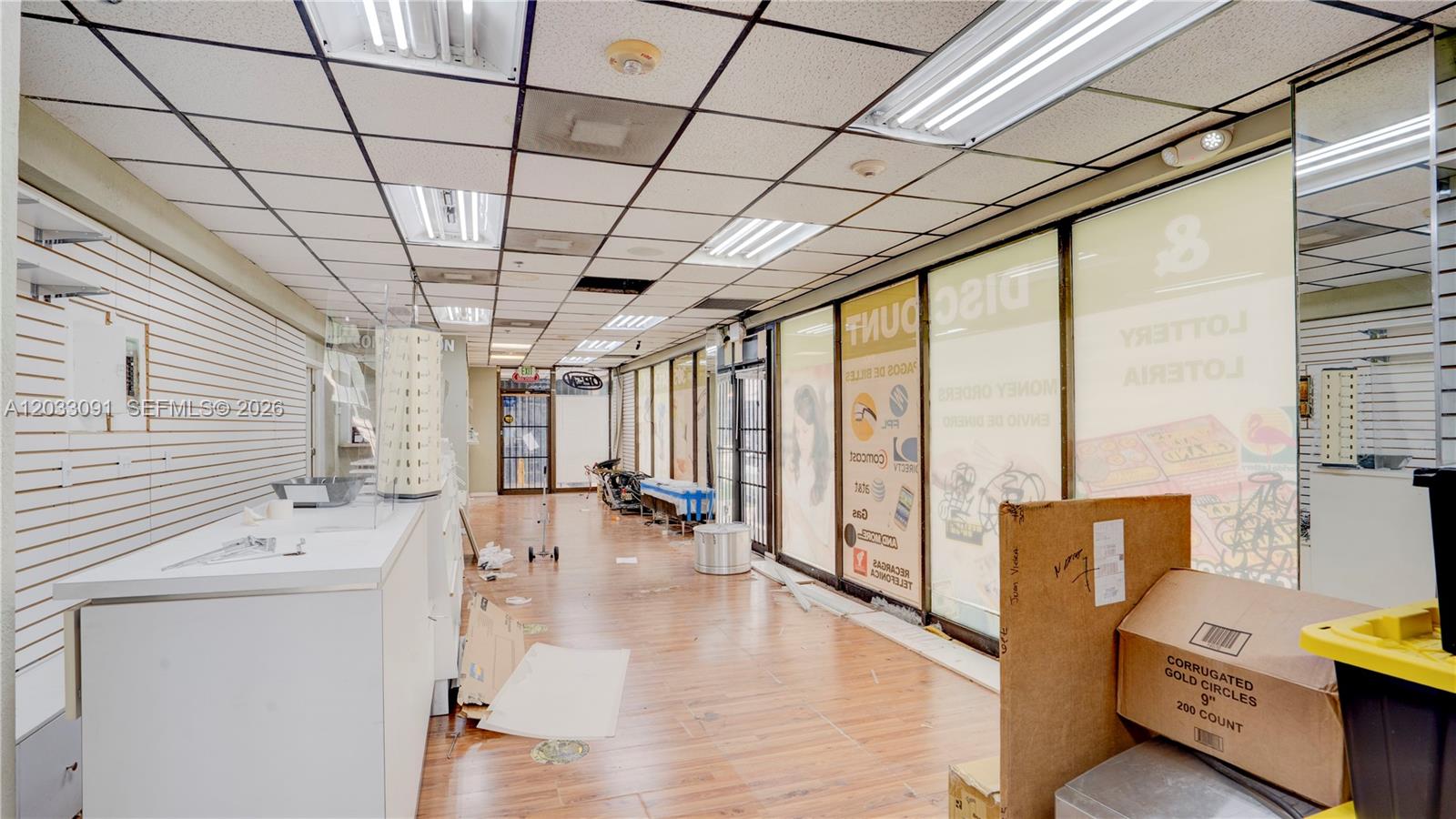 An empty retail space with wood-look flooring, a drop ceiling, and large glass storefront windows — 304 SW 12 Ave, Miami FL 33130, MIAMI, FL