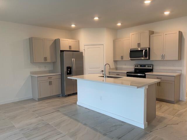 A modern kitchen features light-toned cabinetry, stainless steel appliances, a center island, and tiled flooring — 2751 NE Breezeway Circle, Jensen Beach FL 34957, JENSEN BEACH, FL