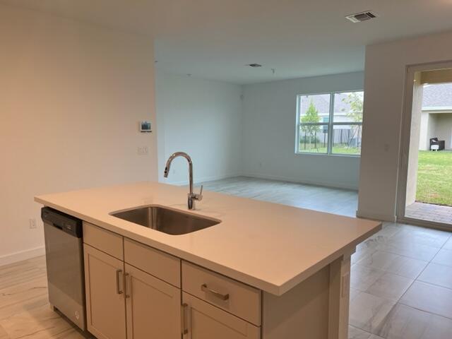 A kitchen island with a stainless steel sink and dishwasher overlooks an open living area — 2751 NE Breezeway Circle, Jensen Beach FL 34957, JENSEN BEACH, FL