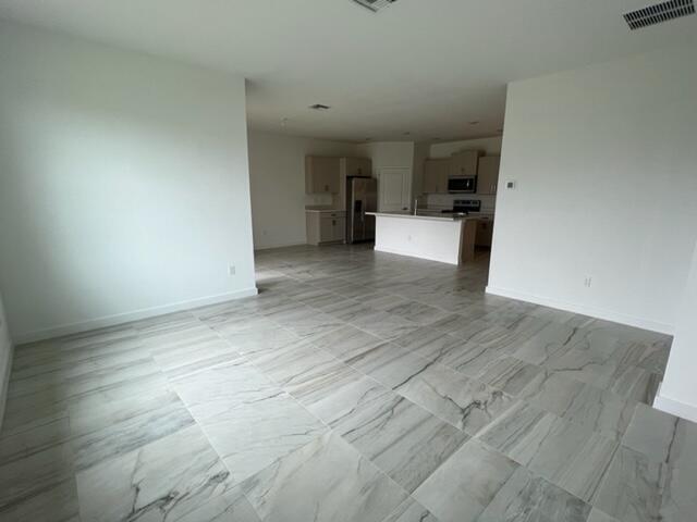 An open-concept kitchen with light-colored cabinets and a center island overlooks a tiled living area — 2751 NE Breezeway Circle, Jensen Beach FL 34957, JENSEN BEACH, FL