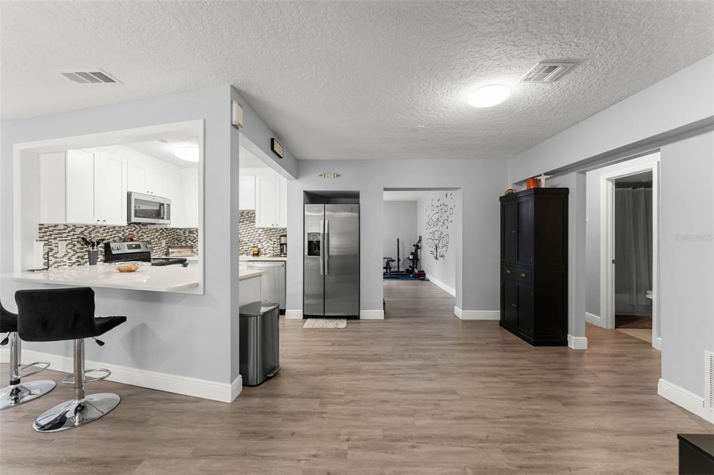A kitchen with a breakfast bar opens into a living area with light wood flooring — 1518 DAROCA DRIVE, DELTONA, FL
