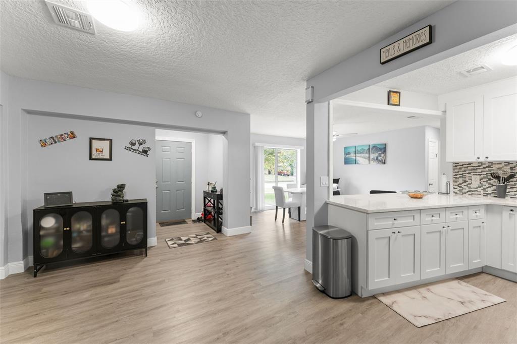 A kitchen with white cabinets and a breakfast bar opens into a light-filled dining area — 1518 DAROCA DRIVE, DELTONA, FL