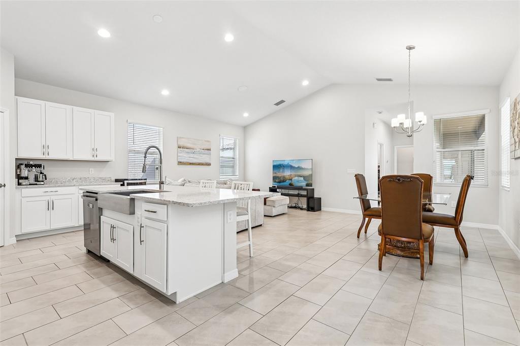 A bright open-concept kitchen and dining area with white cabinetry, granite countertops, and tile flooring — 12103 EASTMOOR DRIVE, WINTER GARDEN, FL