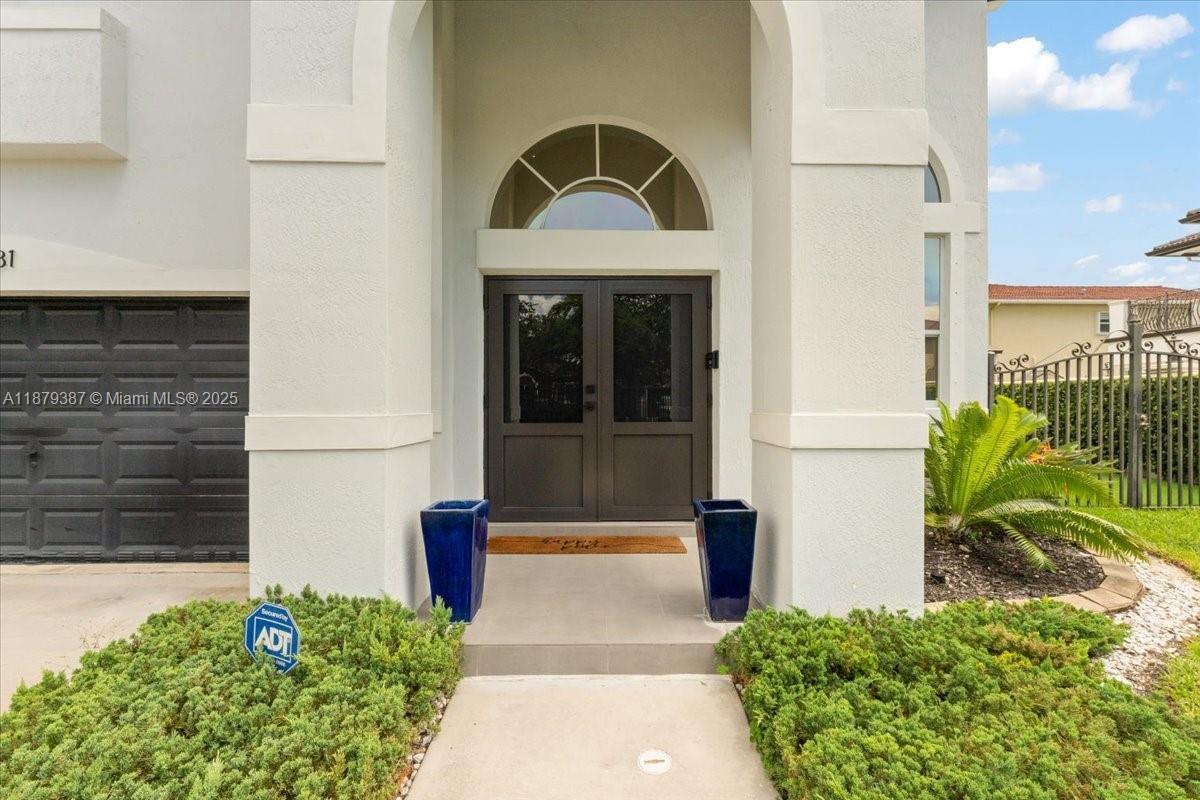 The exterior of a house features a double front door, arched window, and garage — 15931 SW 61st Ln, Miami FL 33193, MIAMI, FL