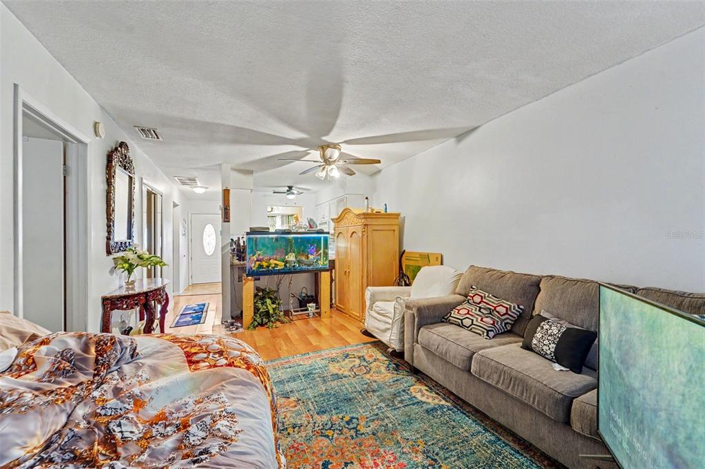 A living room features a grey sofa, a large fish tank, and a patterned area rug — 12435 KNOLLBROOK LANE, HUDSON, FL