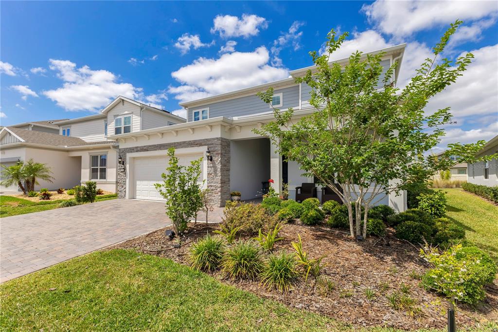 A two-story suburban house features a stone-accented garage, light blue siding, and a landscaped yard — 13330 PANAMA BEACH COURT, ORLANDO, FL