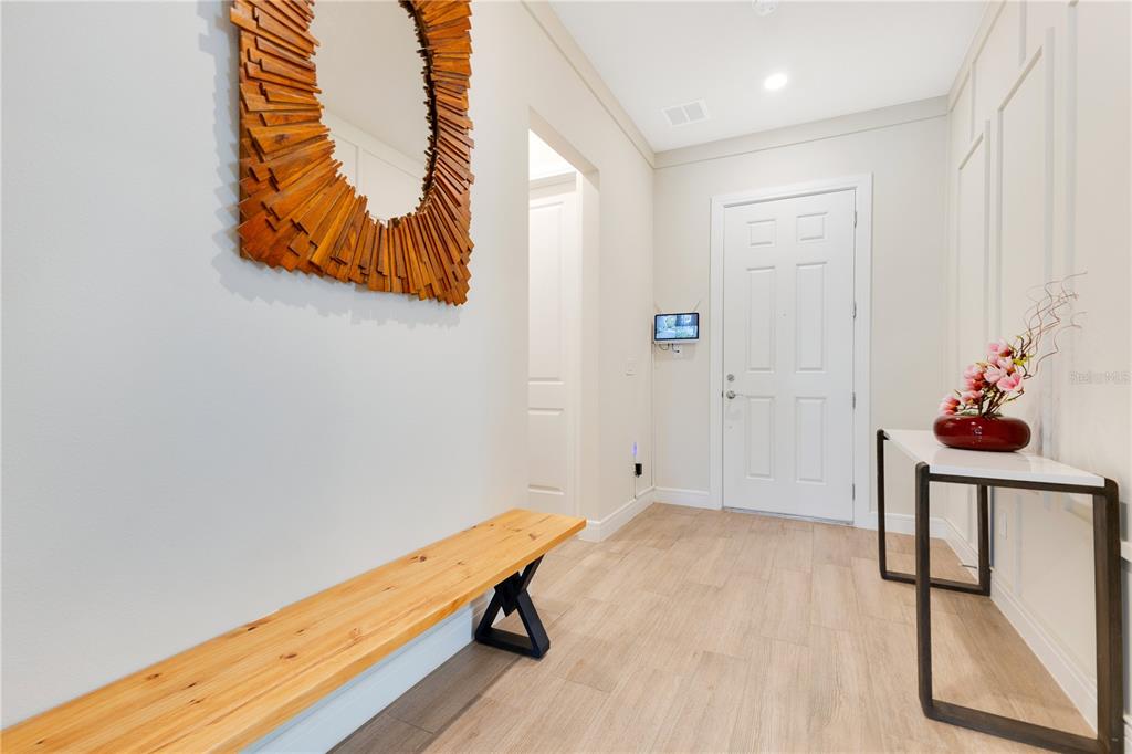 An entryway features light wood flooring, a wooden bench, a console table, and a wall mirror — 13330 PANAMA BEACH COURT, ORLANDO, FL