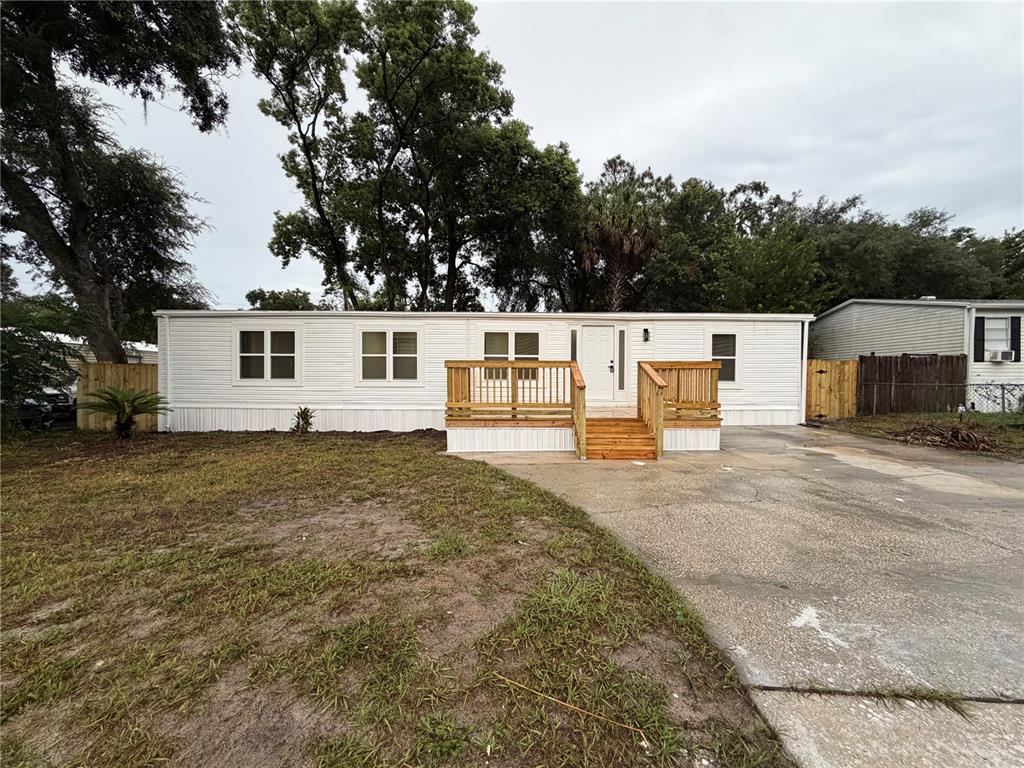 A white single-wide mobile home features a wooden front deck and a concrete driveway — 791 N WINTER PARK DRIVE, CASSELBERRY, FL