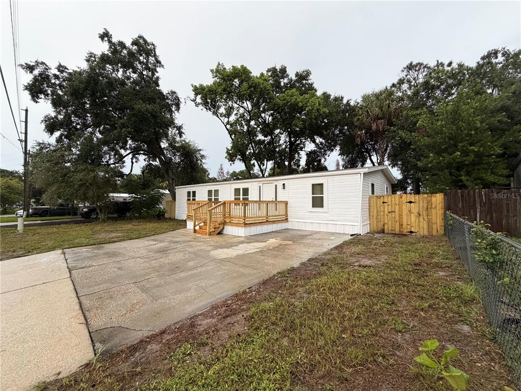 A white manufactured home features a wooden front deck and a concrete driveway — 791 N WINTER PARK DRIVE, CASSELBERRY, FL