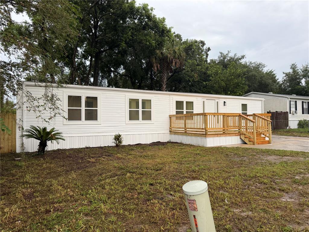 A white mobile home features a new wooden deck and stairs in a grassy yard — 791 N WINTER PARK DRIVE, CASSELBERRY, FL