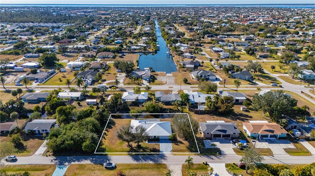 An aerial view shows a single-story house with a white roof near a canal — 3001 VASCO STREET, PUNTA GORDA, FL