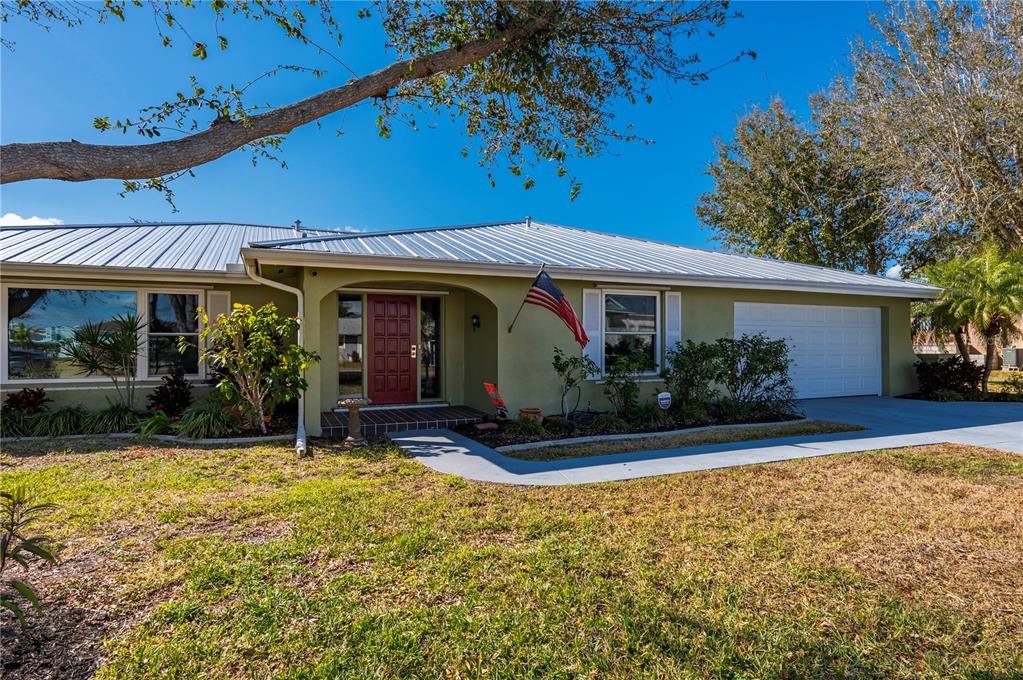 A single-story house with a metal roof, green stucco exterior, and a red front door — 3001 VASCO STREET, PUNTA GORDA, FL