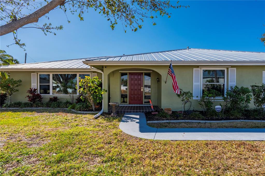 A single-story house with a metal roof, green exterior, and a red front door — 3001 VASCO STREET, PUNTA GORDA, FL