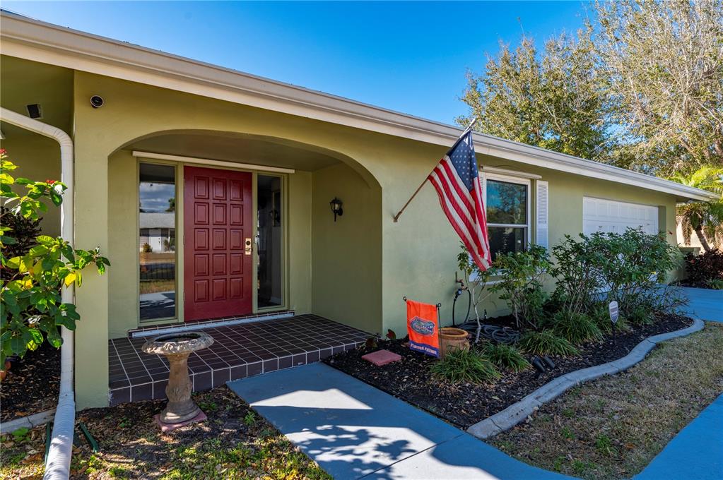 A light green house exterior features a red front door, a porch, and an American flag — 3001 VASCO STREET, PUNTA GORDA, FL
