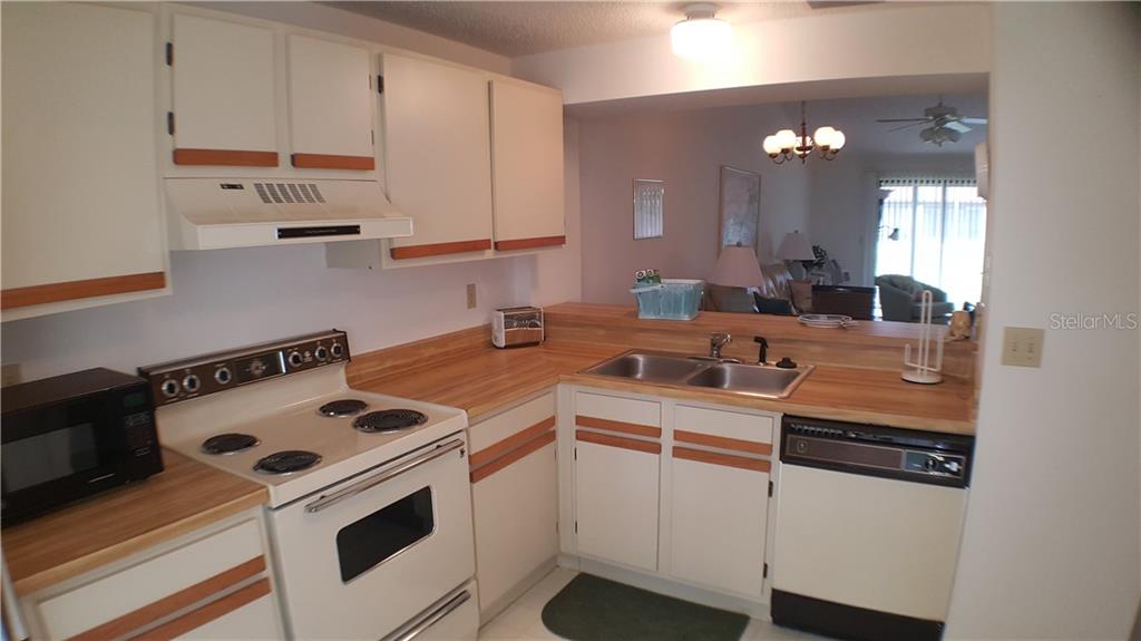 A kitchen with white cabinets, wood trim, laminate countertops, and white appliances — 5907 36TH AVENUE CIRCLE W UNIT 5907, BRADENTON, FL