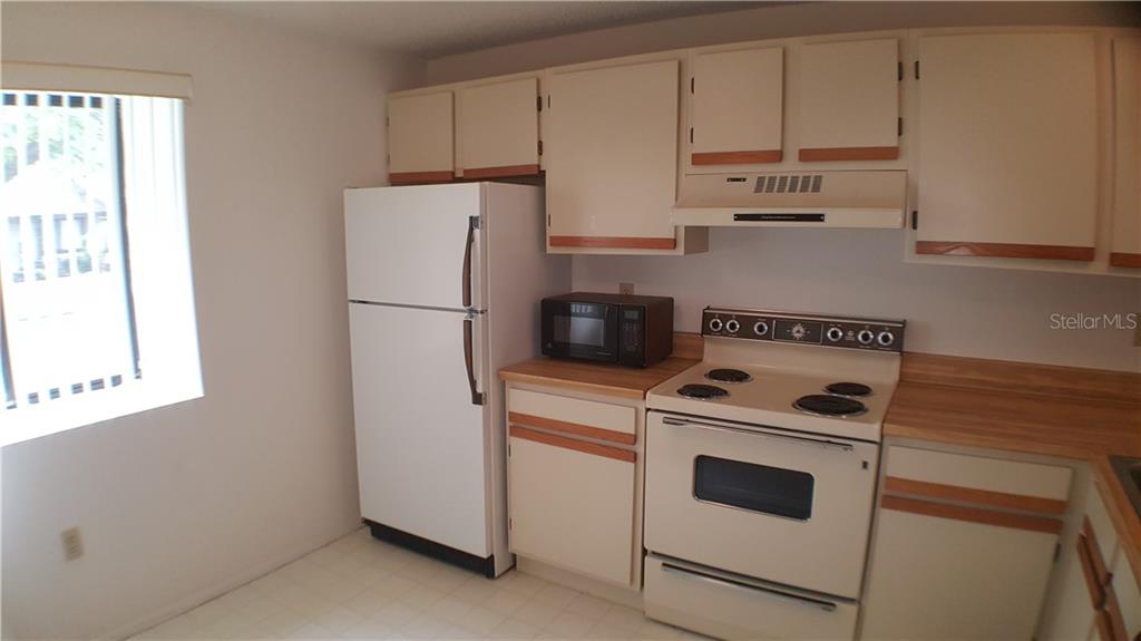 A kitchen with white appliances, light-colored cabinets, and wood-look laminate countertops — 5907 36TH AVENUE CIRCLE W UNIT 5907, BRADENTON, FL