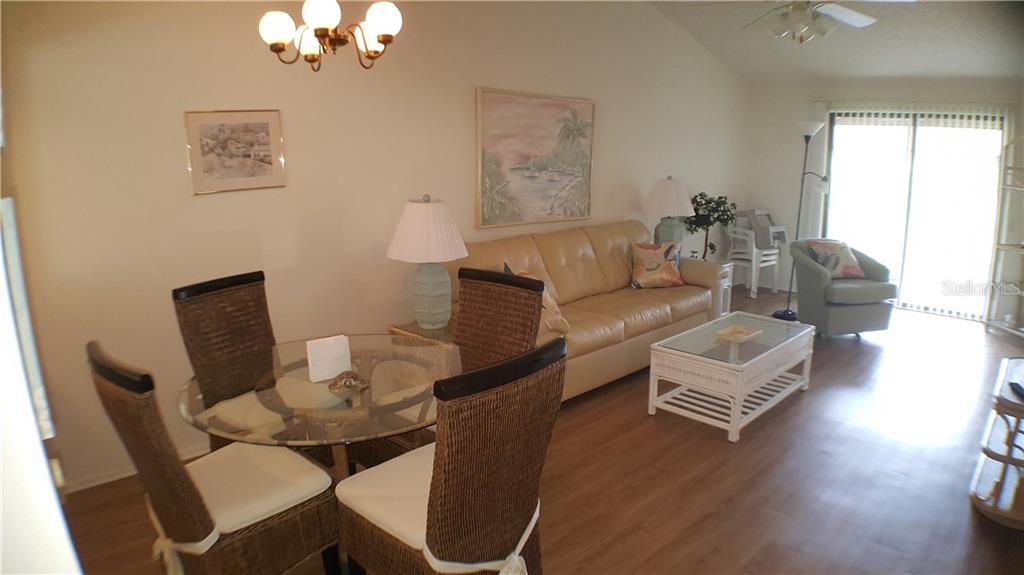 A living and dining area features a glass table, wicker chairs, and a beige sofa — 5907 36TH AVENUE CIRCLE W UNIT 5907, BRADENTON, FL