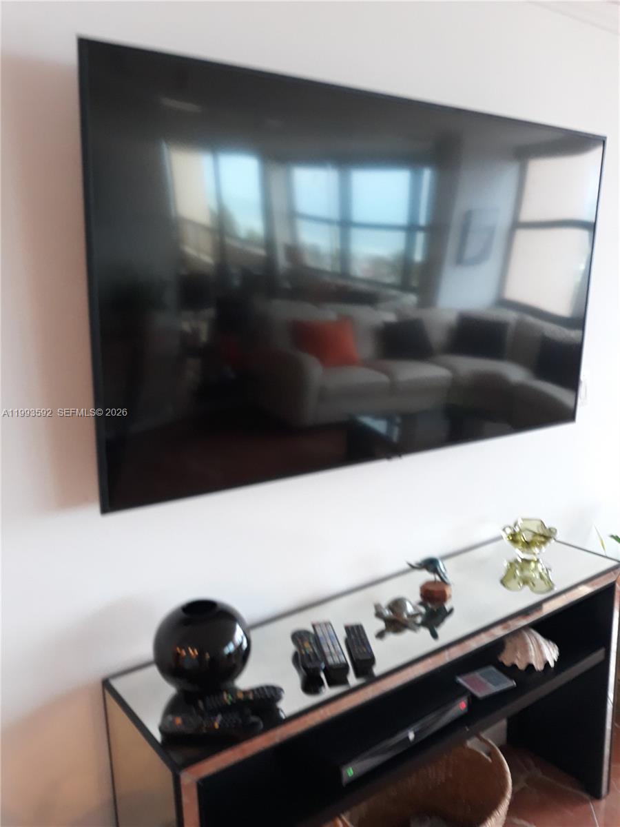 A wall-mounted television hangs above a mirrored console table in a living room — 2555 Collins Ave # 703, Miami Beach FL 33140, MIAMI BEACH, FL