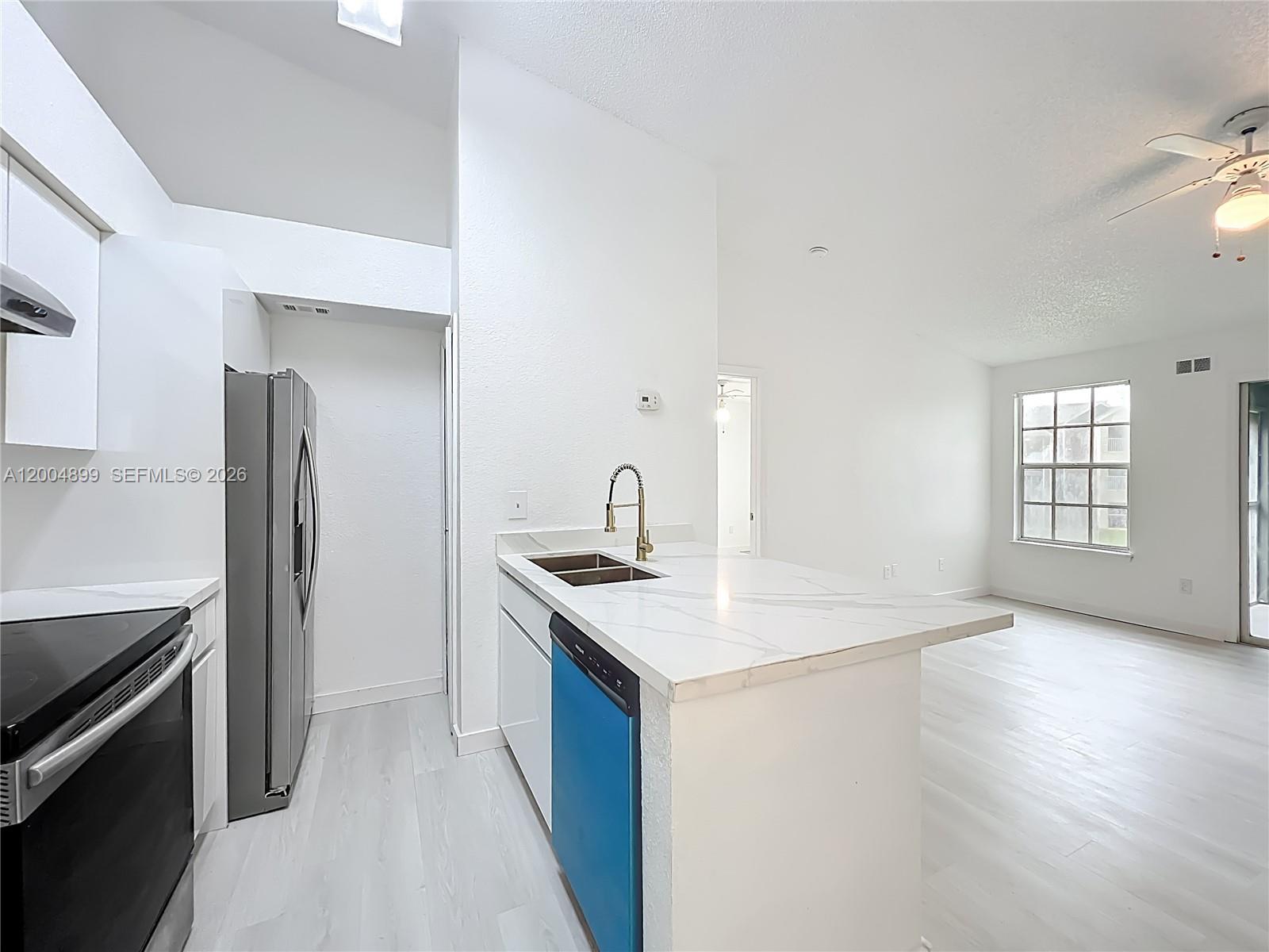 A kitchen features white cabinets, marble-look countertops, stainless steel appliances, and a blue dishwasher — 2225 Metropolitan Way # 1225, Orlando FL 32839, ORLANDO, FL