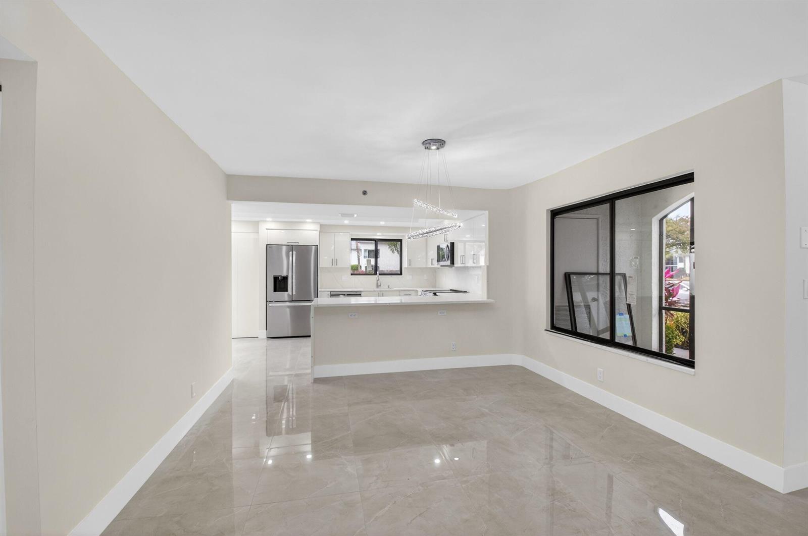 A dining area with tile floors leads to an open kitchen with stainless steel appliances — 15350 Strathearn Drive # 12501, Delray Beach FL 33446, DELRAY BEACH, FL