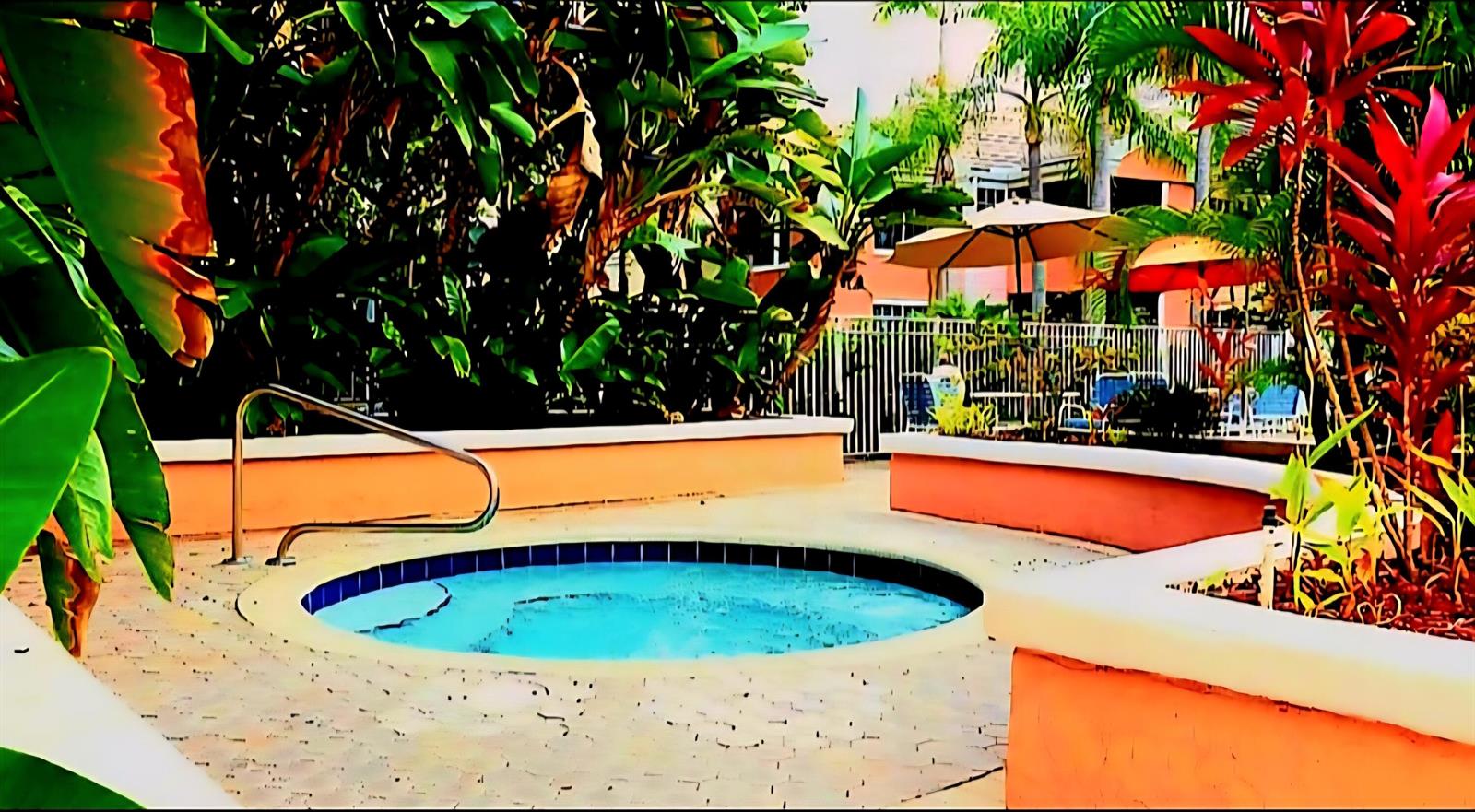 A circular hot tub sits on a paved patio surrounded by lush tropical landscaping — 1020 Crystal Way # L, Delray Beach FL 33444, DELRAY BEACH, FL