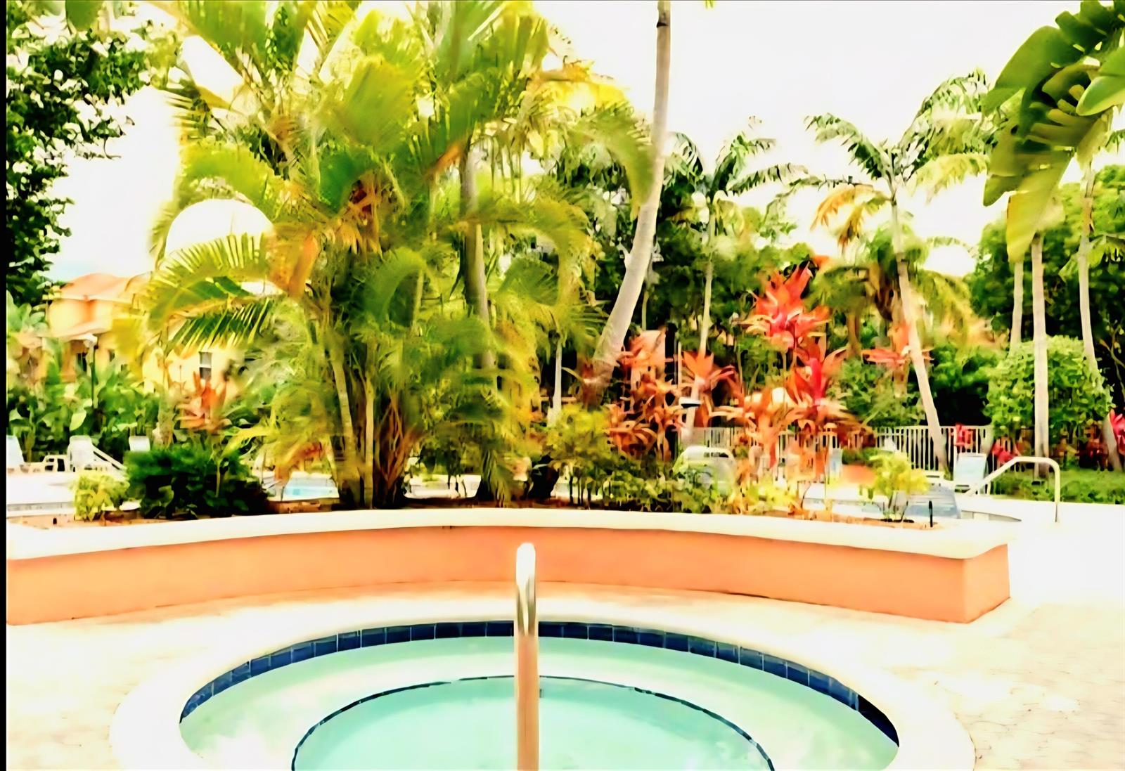 A circular hot tub sits on a patio surrounded by lush tropical landscaping and palm trees — 1020 Crystal Way # L, Delray Beach FL 33444, DELRAY BEACH, FL