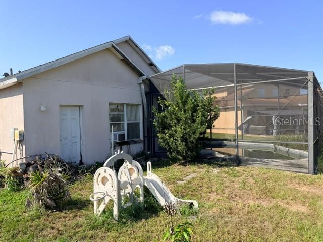The exterior of a house features a screened-in pool enclosure and a plastic playground slide — 719 CORVINA DRIVE, DAVENPORT, FL