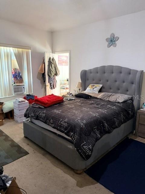 A bedroom features a gray tufted upholstered bed, a window with blinds, and a doorway — 719 CORVINA DRIVE, DAVENPORT, FL