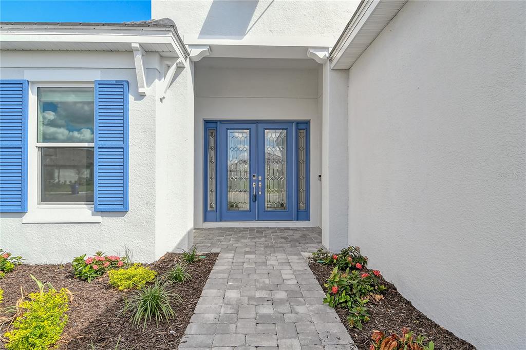 A front entrance with a blue double door, shutters, and a stone paver walkway — 15625 SAN LAZZARO AVENUE, BRADENTON, FL