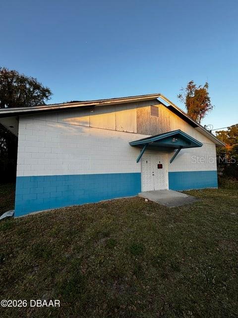 A single-story building with white and blue concrete block walls and a metal entrance awning — 227 W VOORHIS AVENUE, DELAND, FL