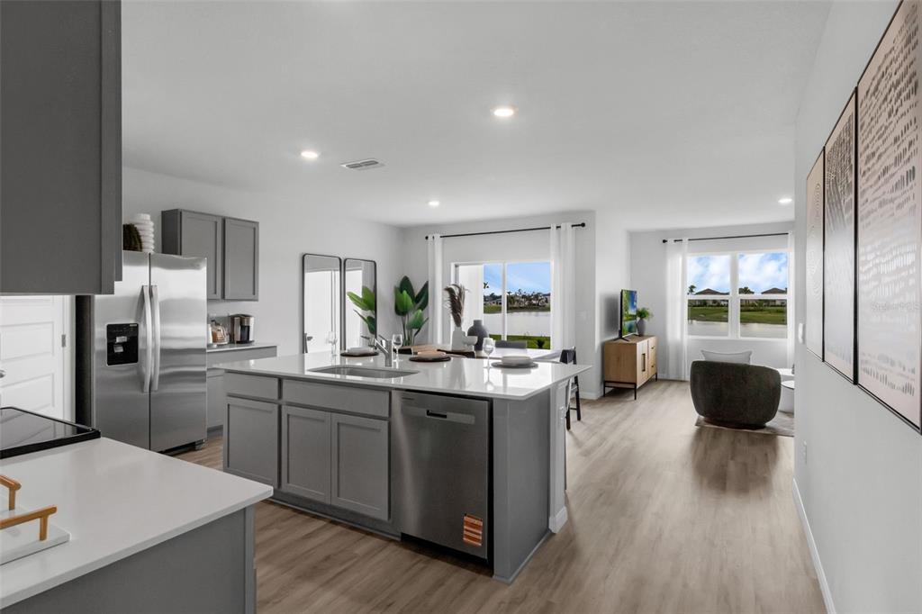 A kitchen with a gray island and stainless steel appliances overlooks a bright living area — 1765 HUMMINGBIRD ROAD, WINTER HAVEN, FL