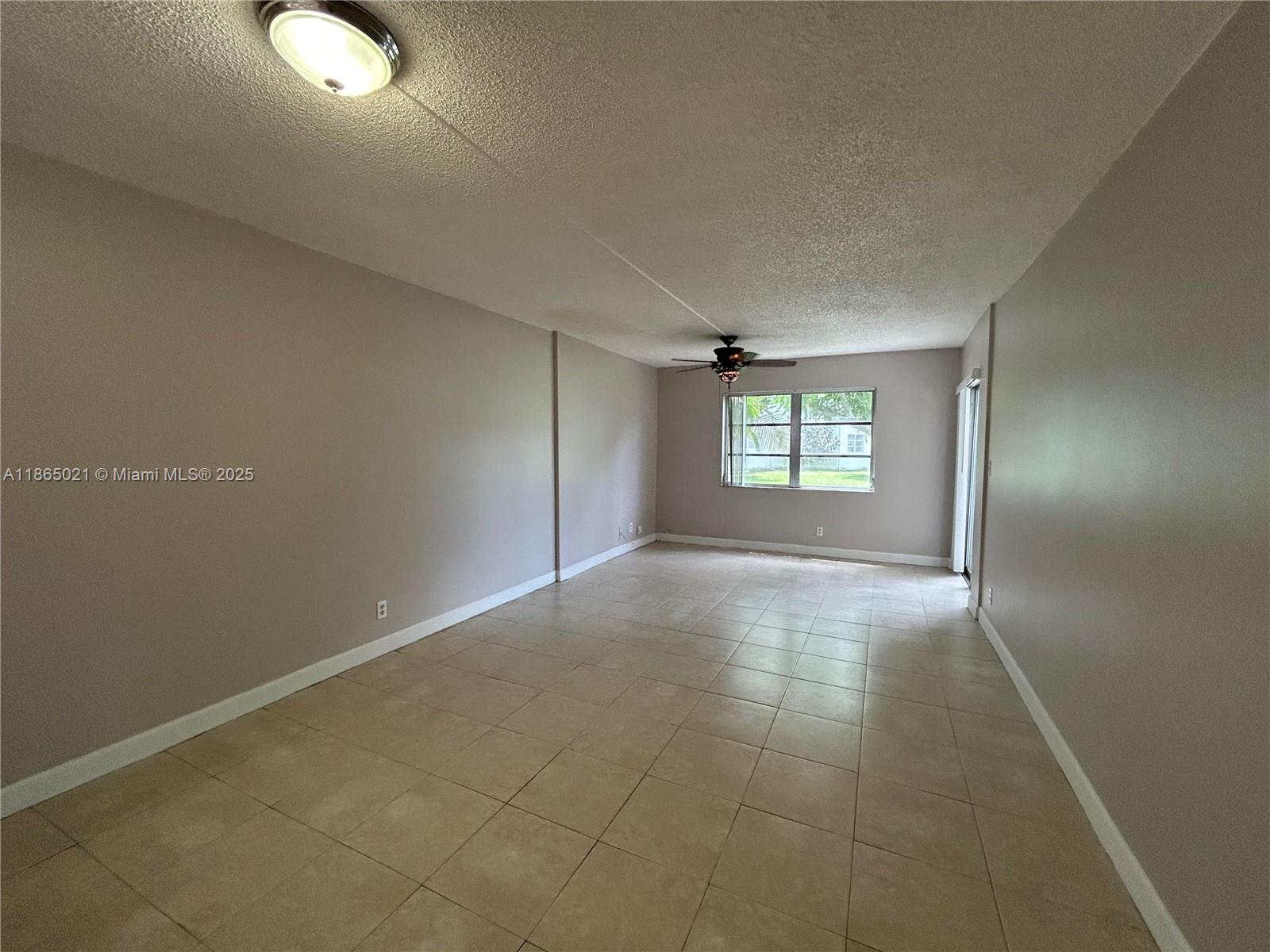An empty room features beige tile flooring, light-colored walls, a ceiling fan, and a window — 6505 Winfield Blvd # 18, Margate FL 33063, MARGATE, FL