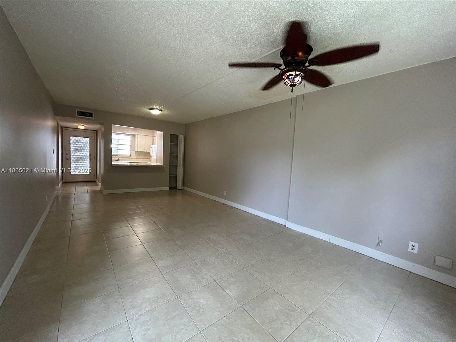 An empty living room features beige tile flooring, gray walls, and a ceiling fan — 6505 Winfield Blvd # 18, Margate FL 33063, MARGATE, FL