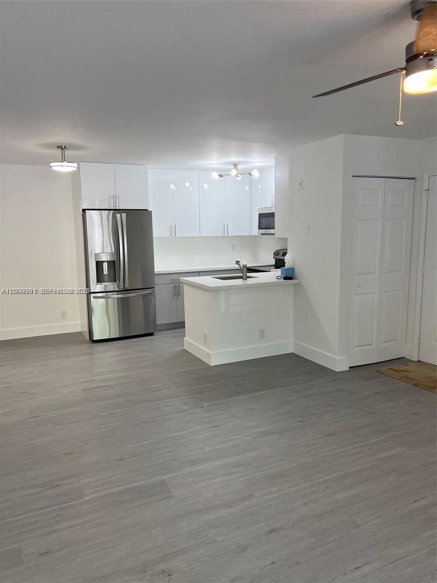A kitchen with white cabinets, stainless steel appliances, and a peninsula counter overlooks a room — 931 Lyons Rd # 4101, Coconut Creek FL 33063, COCONUT CREEK, FL