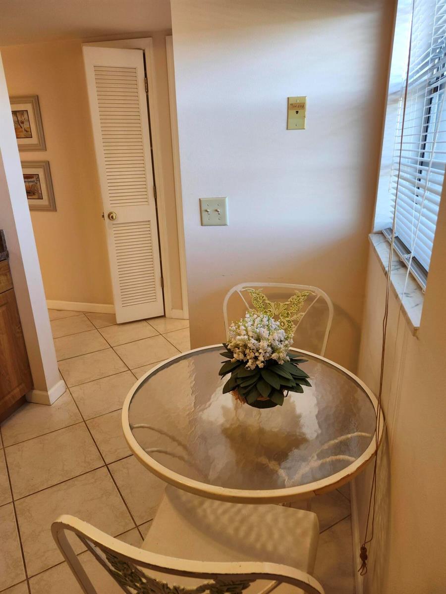 A small breakfast nook features a glass-topped table, two chairs, and tiled flooring — 230 NE 26th Avenue # 408, Boynton Beach FL 33435, BOYNTON BEACH, FL