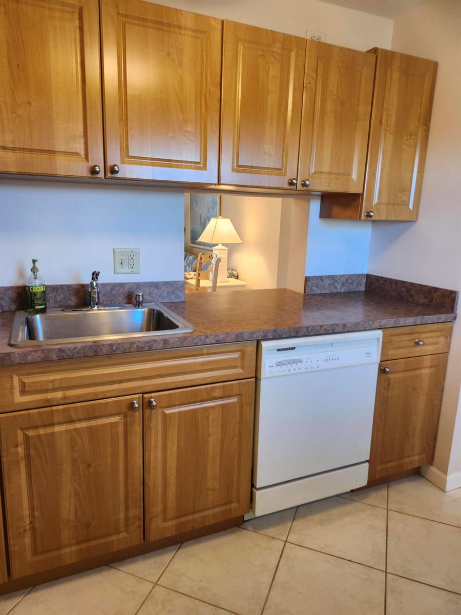 A kitchen features wood cabinets, a laminate countertop, a stainless steel sink, and a dishwasher — 230 NE 26th Avenue # 408, Boynton Beach FL 33435, BOYNTON BEACH, FL